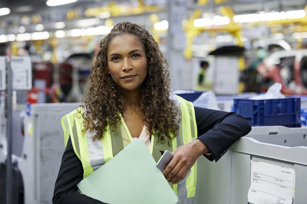 Woman engineer with smart phone in car plant smart codes program