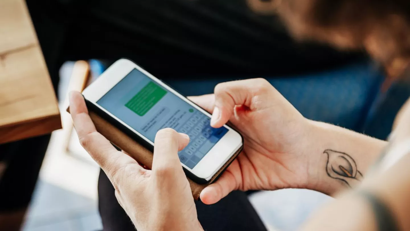 A closeup photo of a woman using a smartphone to send text messages