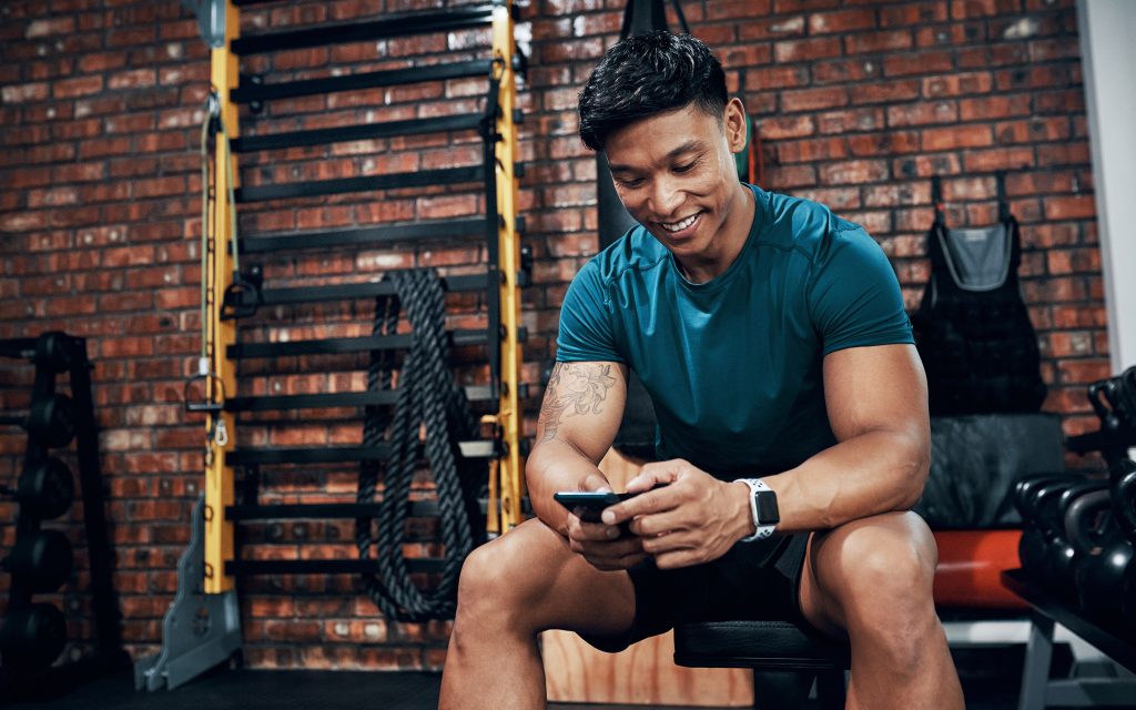 Young man redeeming benefits on his mobile phone at the gym smart codes program